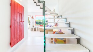 Un intérieur moderne avec un escalier, des murs blancs et une porte rouge.