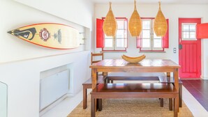 Un coin repas avec une table en bois, des suspensions en osier et une décoration sur le thème du surf.