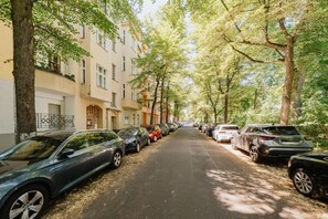A tree-lined street with parked cars and residential buildings. - Boutique Urban Nest | Cozy & Central 1 (Berlin)