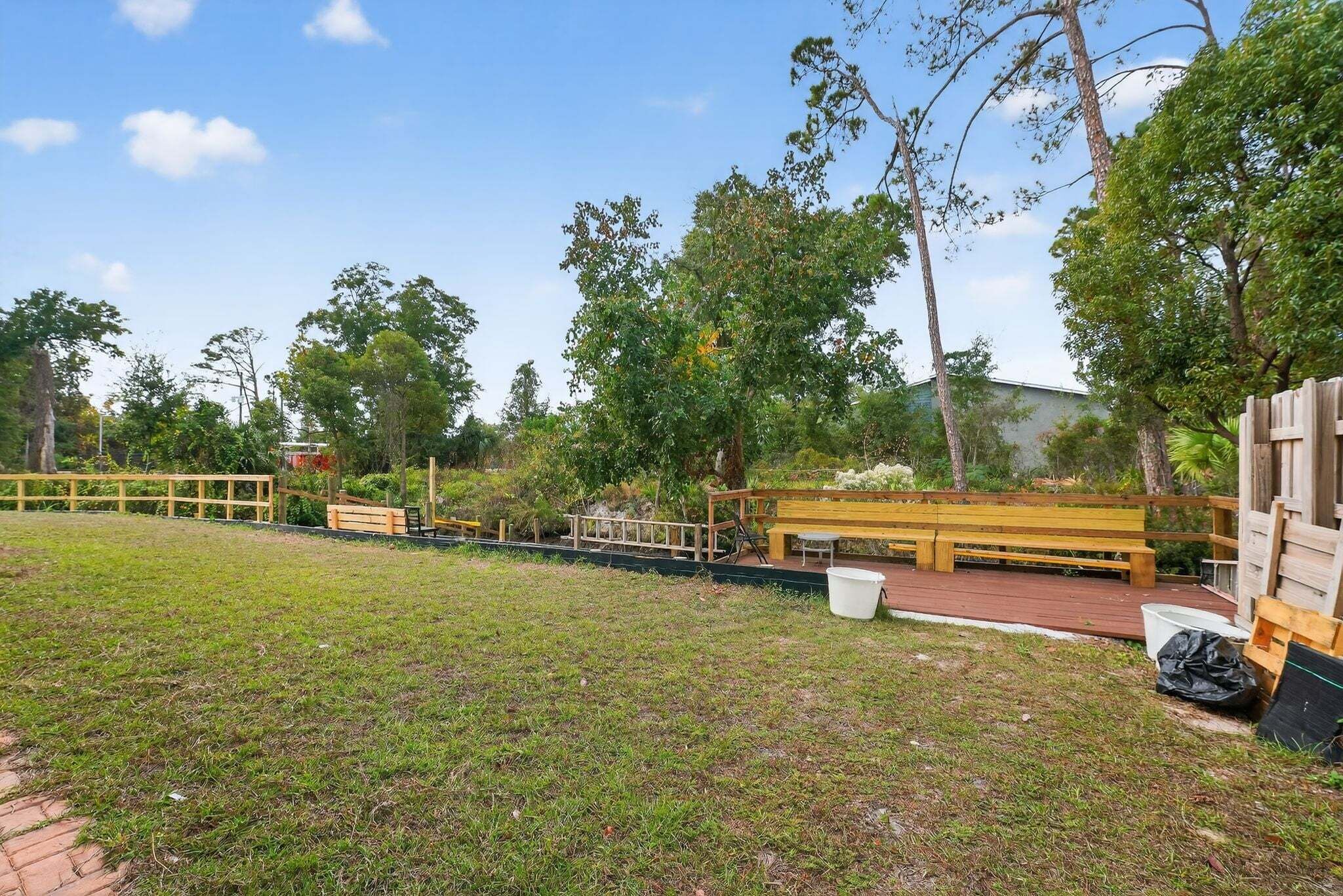 Un espacio al aire libre con césped, bancos de madera y una terraza de madera.