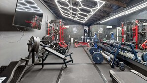 A gym with weightlifting equipment, mirrors, and a geometric ceiling design. - Healing Adventures Wellness Retreat 3 Bedroom Home (Claxton)