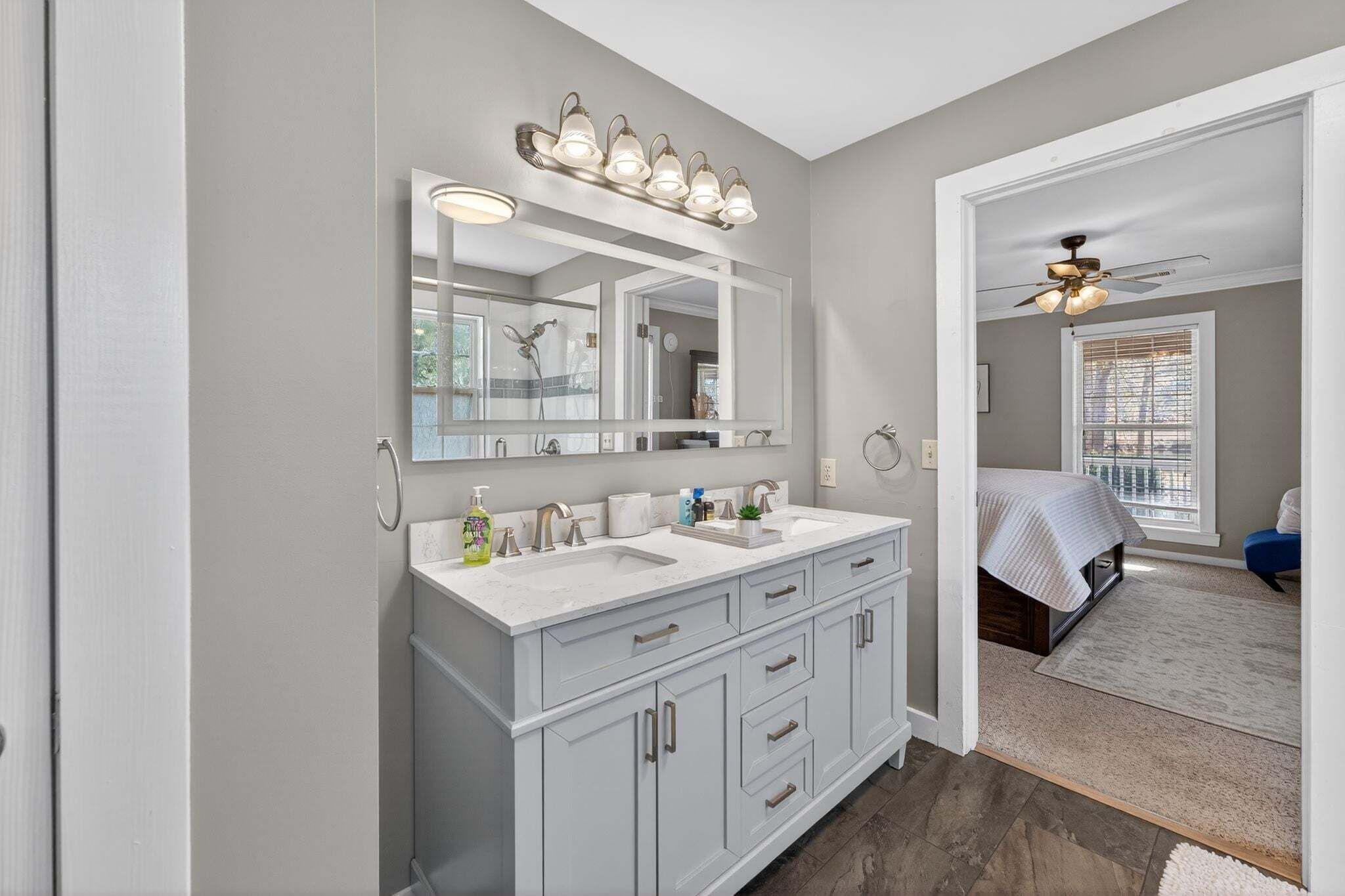 Une salle de bain avec deux lavabos, un grand miroir et un ventilateur de plafond.