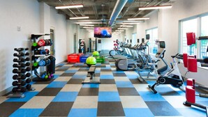 Une salle de sport équipée de divers appareils d’exercice, notamment des haltères, des kettlebells et des appareils de cardio.