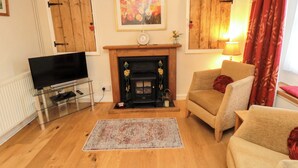 A living room with a fireplace, a television, and a sofa. - Beacon Cottage (Pickering)