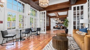 A spacious room with large windows, a fireplace, and a cozy seating area with a sofa and chairs.
