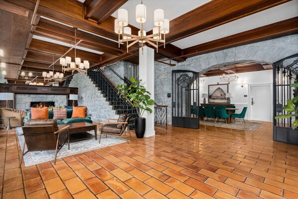 A spacious lobby with a high ceiling, exposed wooden beams, a fireplace, and a staircase leading to upper floors. - Sonoma Stonehouse Retreat • Chic King Room (Santa Rosa)