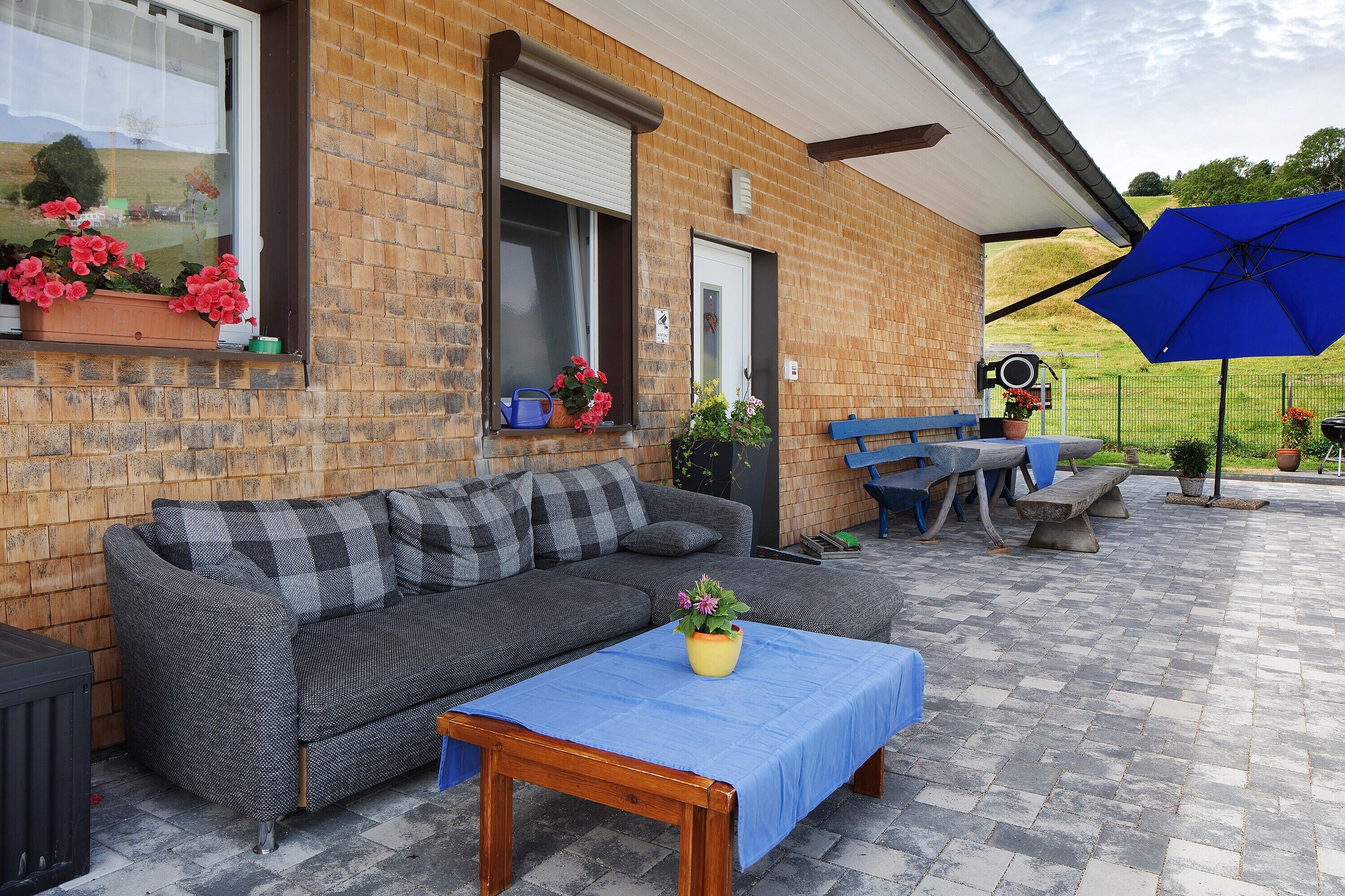 Une maison en briques dotée d’un patio comprenant un canapé, une table et des sièges d’extérieur.