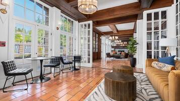 A spacious room with large windows, a fireplace, and a cozy seating area with a sofa and chairs.