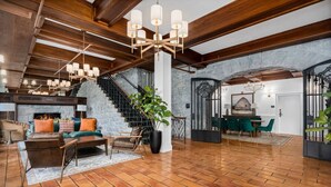 A spacious living area with a fireplace, wooden beams, and a staircase.
