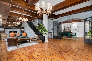 A spacious living area with a fireplace, wooden beams, and a staircase.