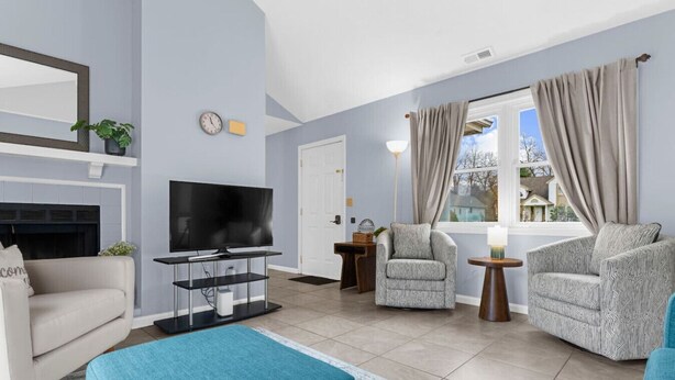 Een woonkamer met een televisie, banken, fauteuils en een open haard.