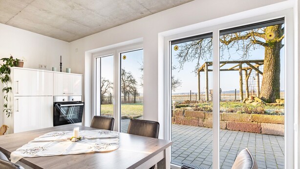 A modern kitchen with a dining area, large windows, and a view of the outdoors. - Apartment 'Seyfried' with Private Terrace, Shared Garden and Wi-Fi (Hardheim)