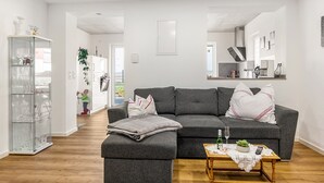 A modern living room with a grey sectional sofa, a glass cabinet, and a wooden coffee table. - Apartment 'Seyfried' with Private Terrace, Shared Garden and Wi-Fi (Hardheim)