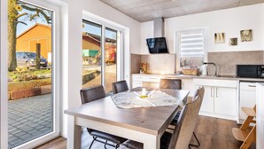 A modern kitchen with white cabinets, a microwave, and a dining area with a table and chairs. - Apartment 'Seyfried' with Private Terrace, Shared Garden and Wi-Fi (Hardheim)