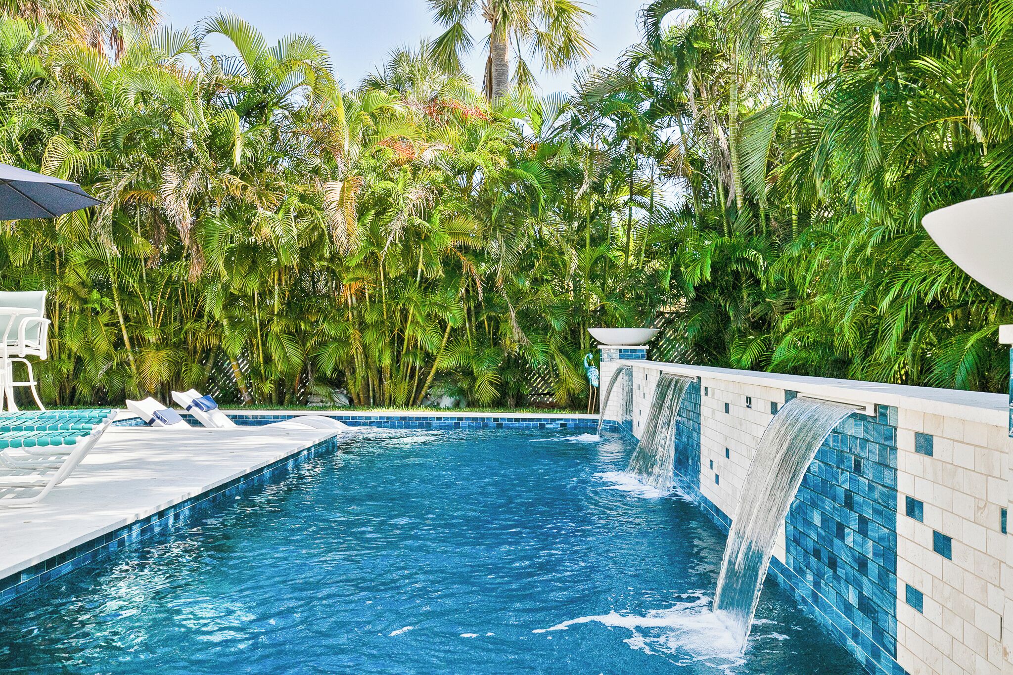 Una piscina con cascata, immersa in una rigogliosa vegetazione tropicale.