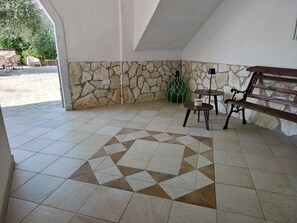 A room with a stone wall, a tiled floor with a geometric pattern, a bench, and a small table. - Apartment on the ground floor of panoramic villa (Peschici)