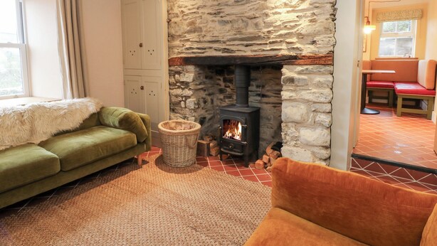 Una sala de estar acogedora con una chimenea de piedra, un sofá verde y un sillón rojo.