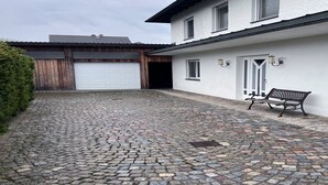 Un vialetto in pietra che conduce a un edificio bianco con un garage, una panchina e un piccolo giardino.