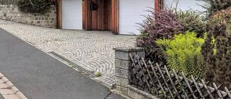 A two-story house with a wooden exterior, a garage, and a paved driveway.