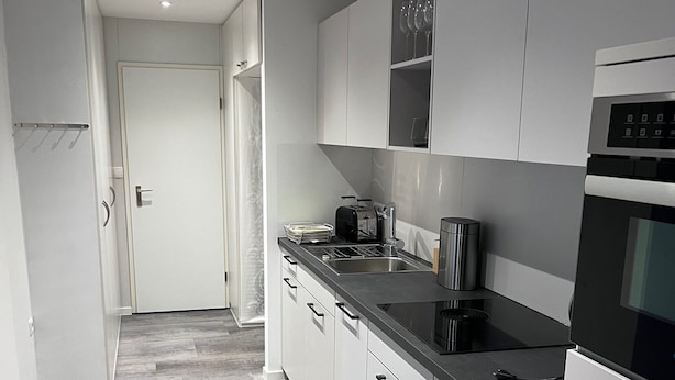 Una cucina moderna con mobili bianchi, un piano di lavoro nero e un lavello in acciaio inossidabile.