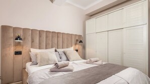 A bedroom with a large bed, two bedside lamps, a wardrobe, and a ceiling light. - Villa Chiara Opatija Apartment Moderna (Ičići)