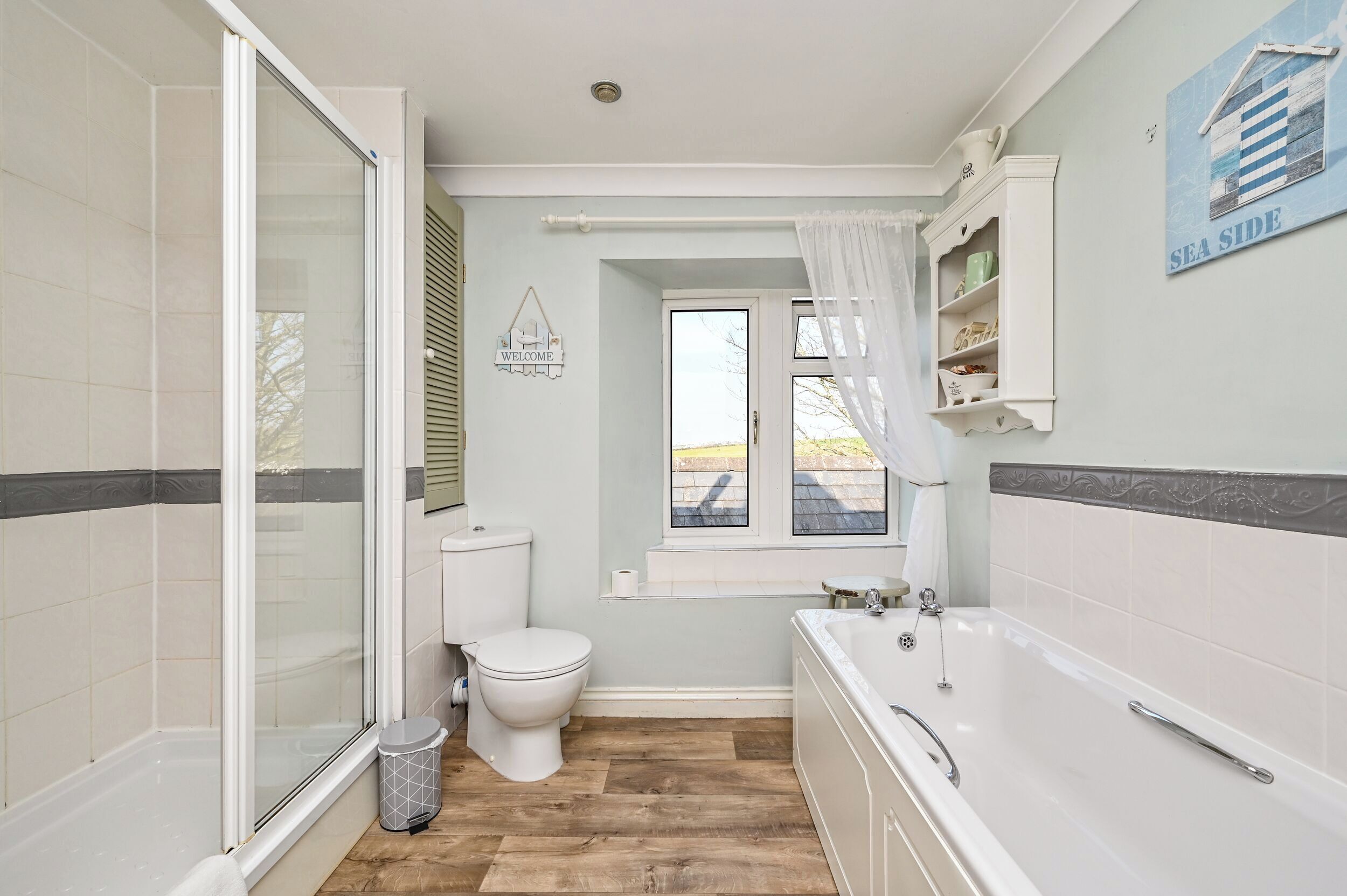 Une salle de bain équipée d’une douche, de toilettes, d’une baignoire et d’une fenêtre donnant sur un paysage agréable.