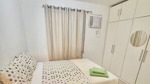 Una camera da letto con un letto, un armadio, una tenda e una radio fissata al muro.