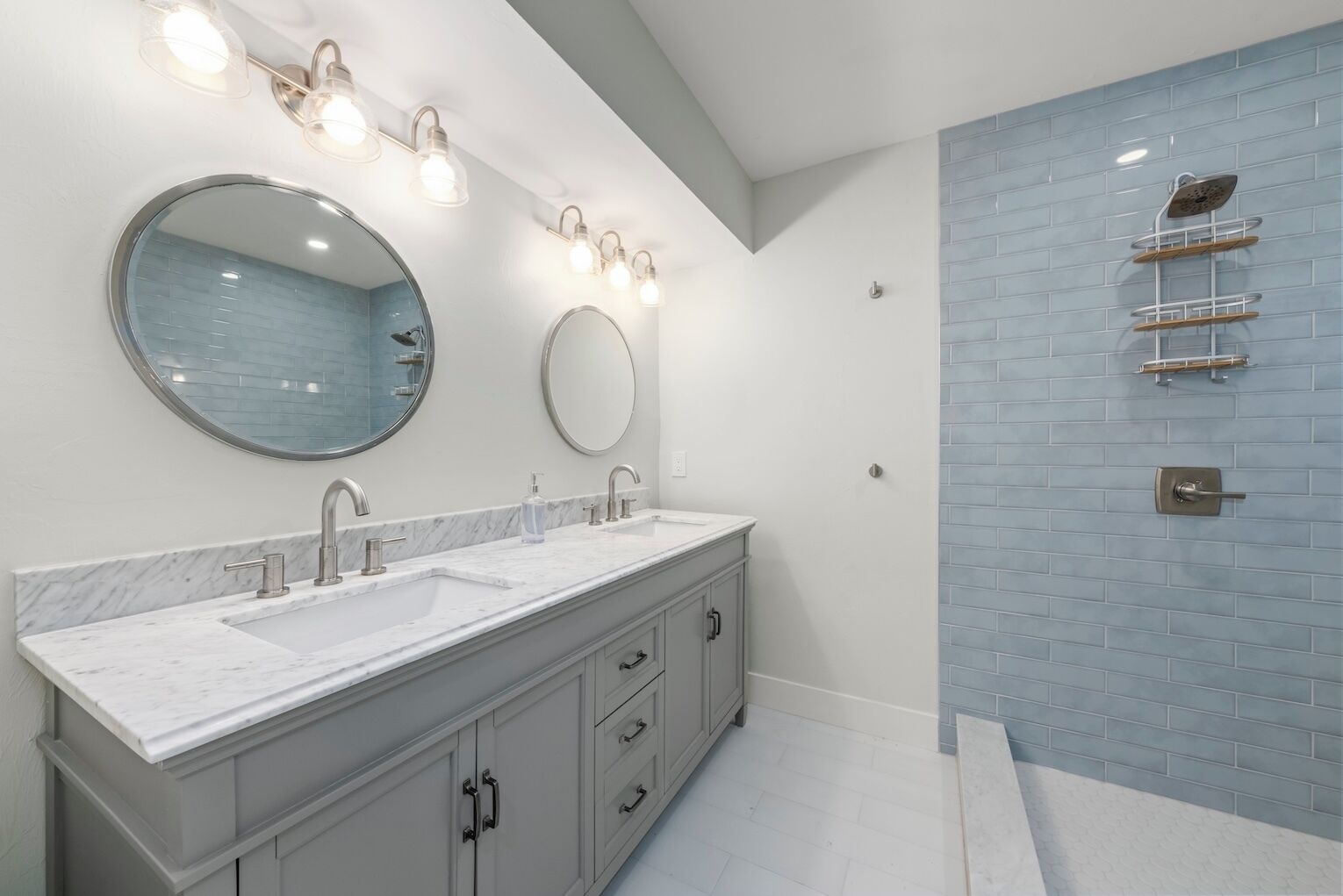 A modern bathroom with two sinks, a large mirror, and a shower with a glass enclosure.