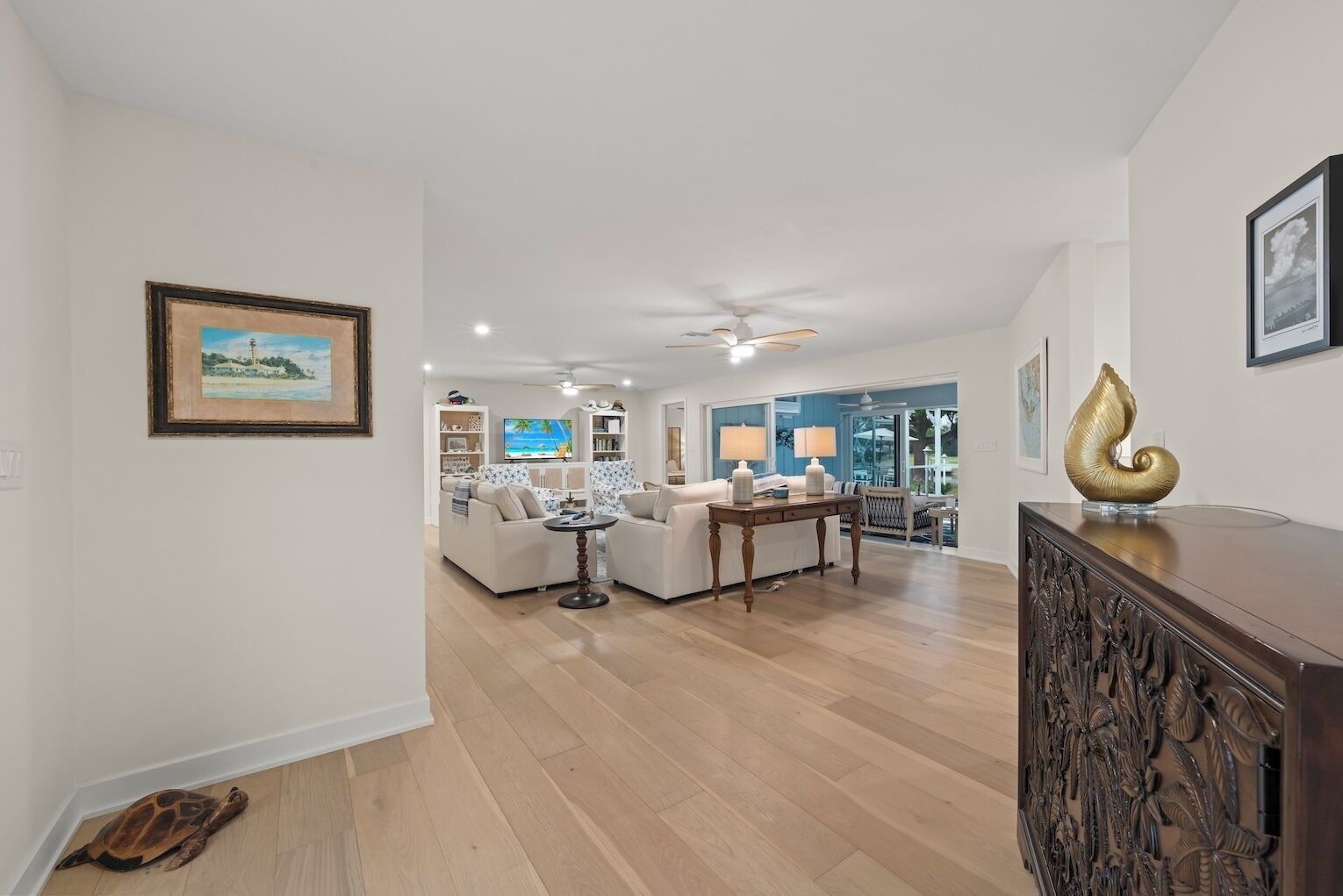 A spacious living room with a white sofa, a wooden coffee table, and a TV in the background.