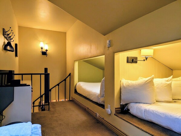 A hotel room with a single bed, a small desk, a chair, a mirror, a wall-mounted lamp, and a staircase leading to an upper level. - New Listing: Pool, Hot Tub, Free shuttle (Keystone)