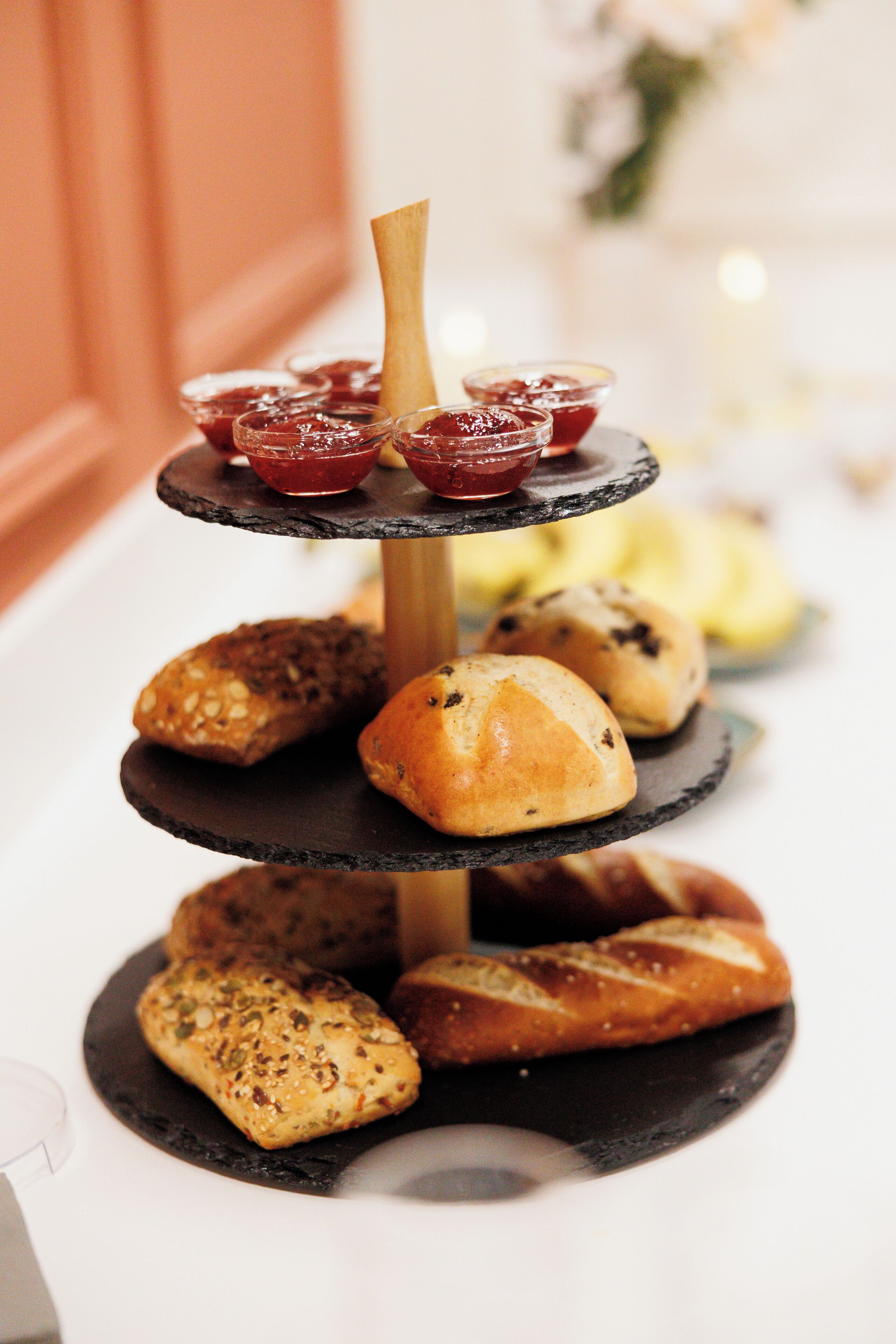 A multi-tiered serving tray with various baked goods and jams.