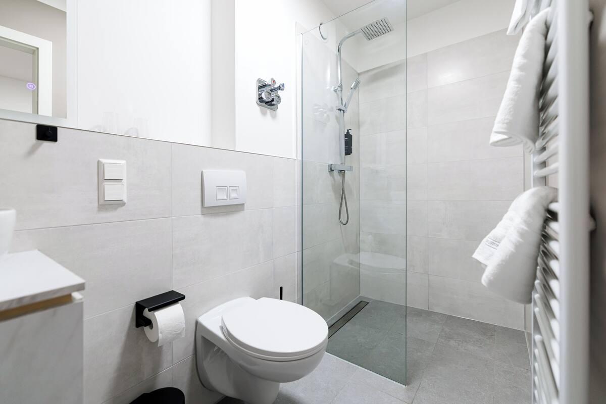 A modern bathroom with a toilet, a glass-enclosed shower, and a towel rack.