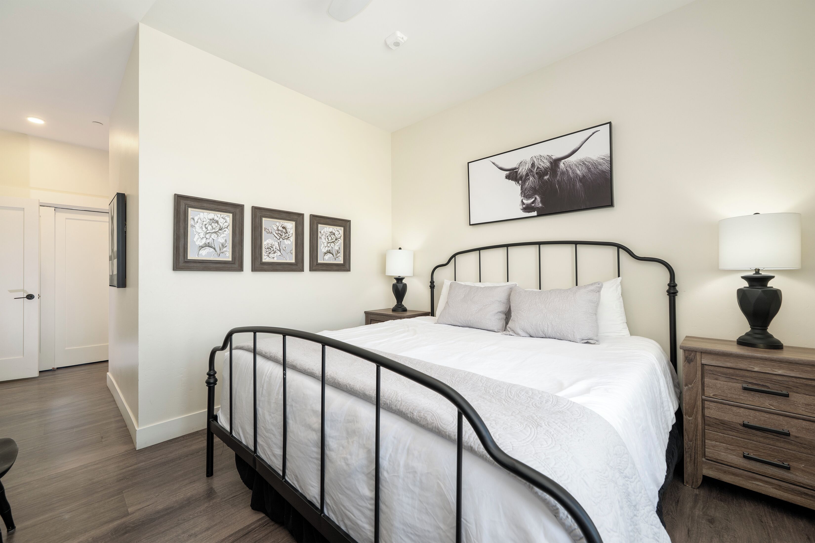 Un dormitorio con cama, mesitas de noche, lámpara y decoración en la pared.