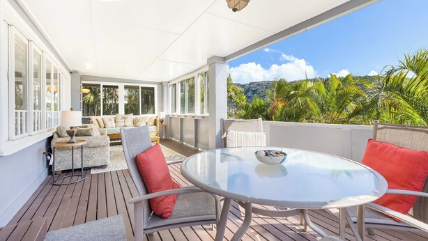 A covered outdoor seating area with a glass table and chairs, a sofa, and a ceiling fan. - Hale Ho‘omalie- Peaceful Mānoa Valley Retreat near UH (Honolulu)