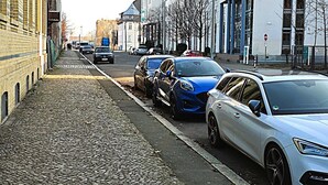 A cobblestone street lined with parked cars and buildings. - UNEA Aparthotel Leipzig (Leipzig)