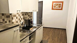 A modern kitchen with a dark wood floor, white cabinets, and a tiled backsplash. - UNEA Aparthotel Leipzig (Leipzig)