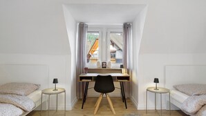 Une chambre avec un bureau, deux tables de chevet, une chaise et un lit.