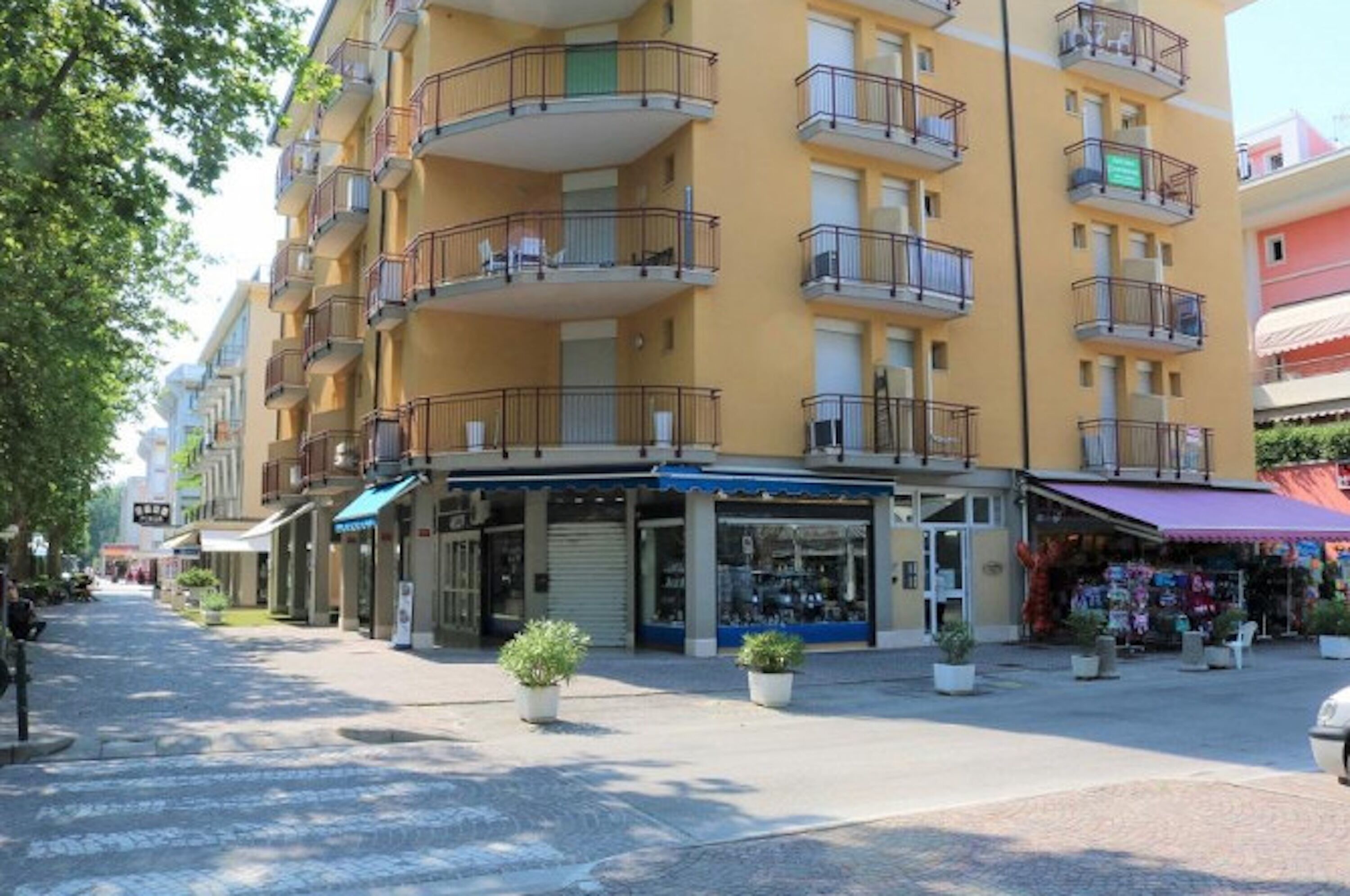 Un edificio de varios pisos con balcones, escaparates y plantas en macetas.