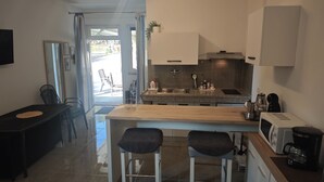 A modern kitchen with a central island, a dining area with a table and chairs, and a view through a glass door. - Studio apartment Flora by Villas Guide (Pula)