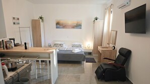 A modern bedroom with a bed, bedside table, and a TV mounted on the wall. - Studio apartment Flora by Villas Guide (Pula)