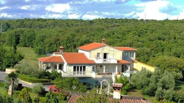 A two-story house with a red-tiled roof, surrounded by lush greenery and a hilly landscape. - Studio apartment Flora by Villas Guide (Pula)