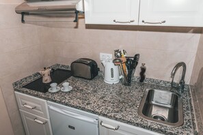 A kitchen with a granite countertop, a toaster, a kettle, and a sink.