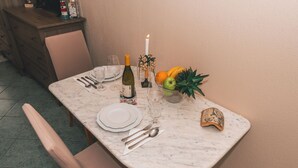 A dining table set with plates, cutlery, a bottle of wine, glasses, a candle, and a fruit bowl. - Villa Chiara Opatija Apartment Rustica (Ičići)