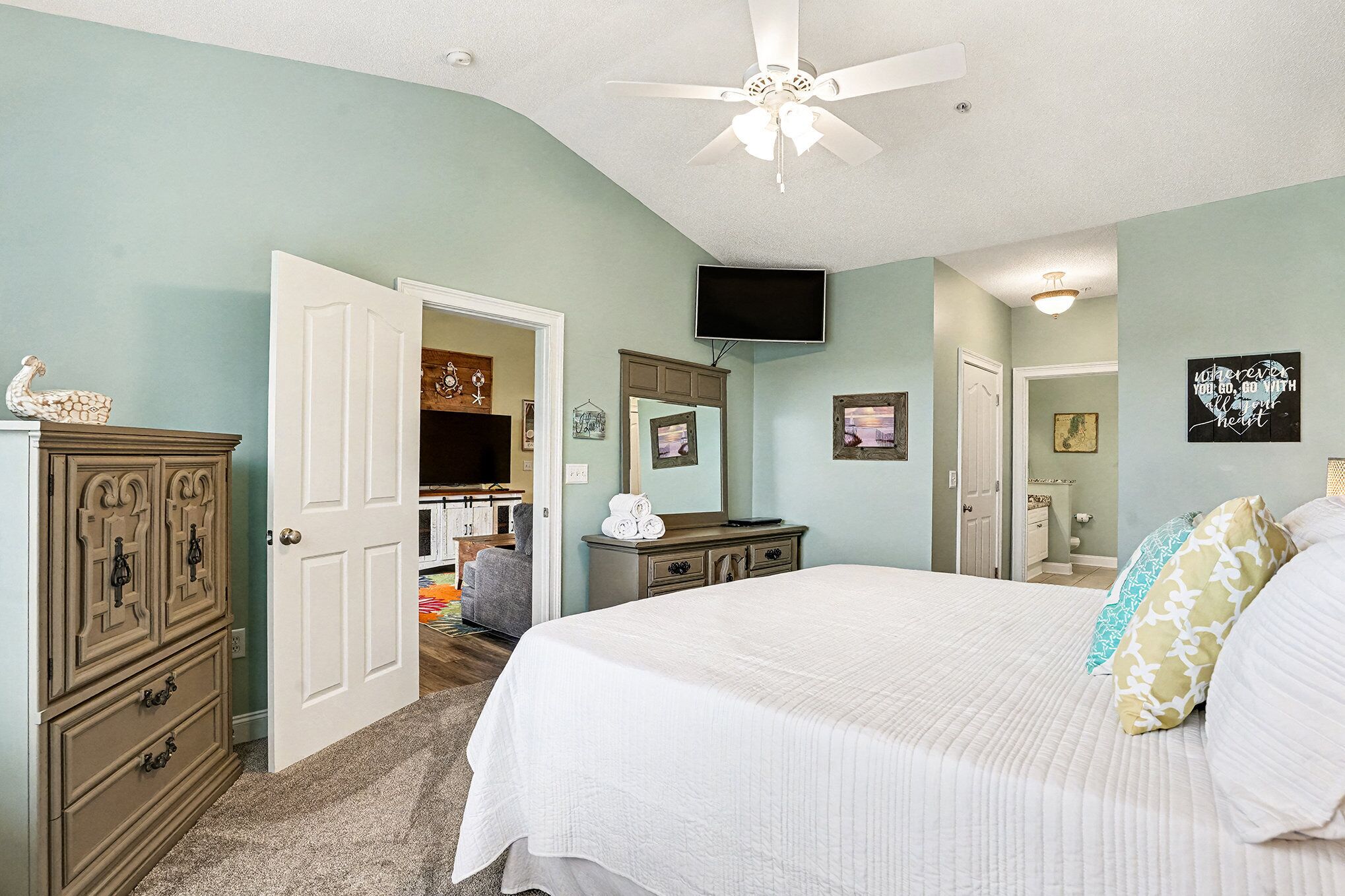 A bedroom with a bed, dresser, and a ceiling fan.
