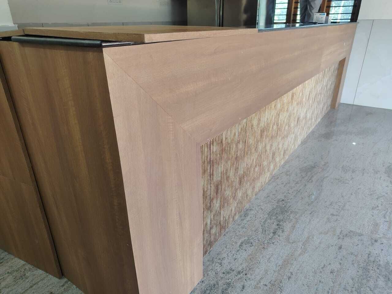 A reception desk with a wooden finish and a glass partition.