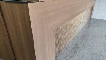 A reception desk with a wooden finish and a glass partition.