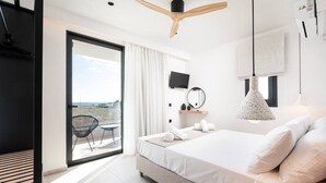 Une chambre moderne avec un grand lit, un ventilateur de plafond, une télévision et une vue sur la plage.