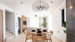 Un espace de salle à manger moderne, avec une table ronde, des chaises en bois et un luminaire au plafond au design original.