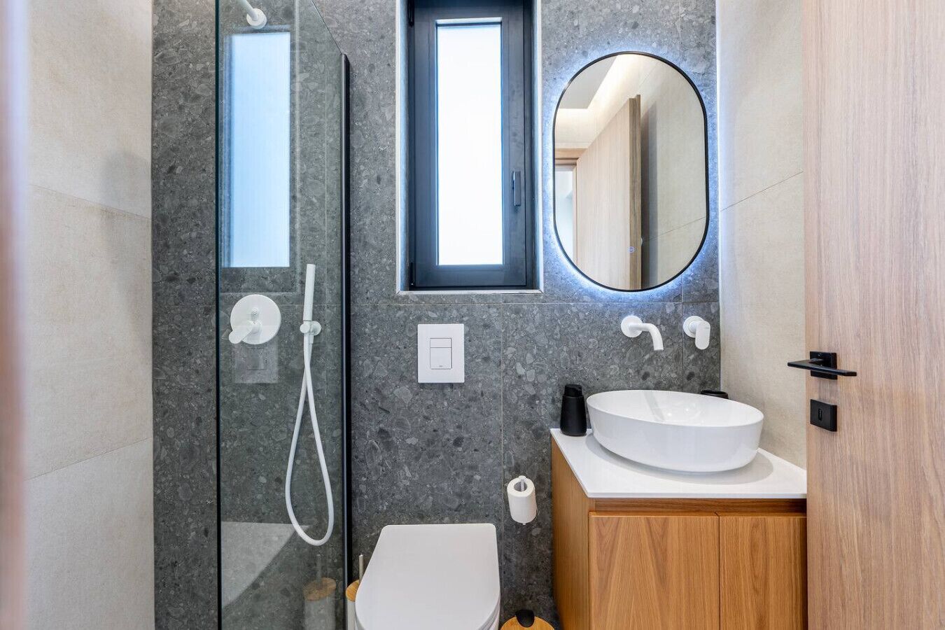 Une salle de bain moderne avec une douche à parois de verre, un lavabo blanc et un meuble-lavabo en bois.