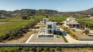 Une villa moderne dotée d’une piscine, entourée d’une végétation luxuriante et d’un paysage vallonné.